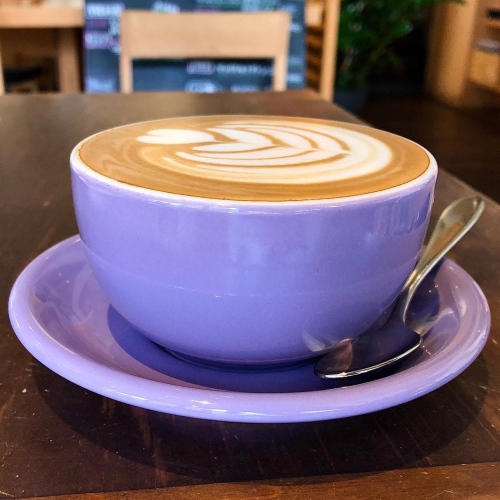 a cafe latte in a purple cup with saucer at a cafe